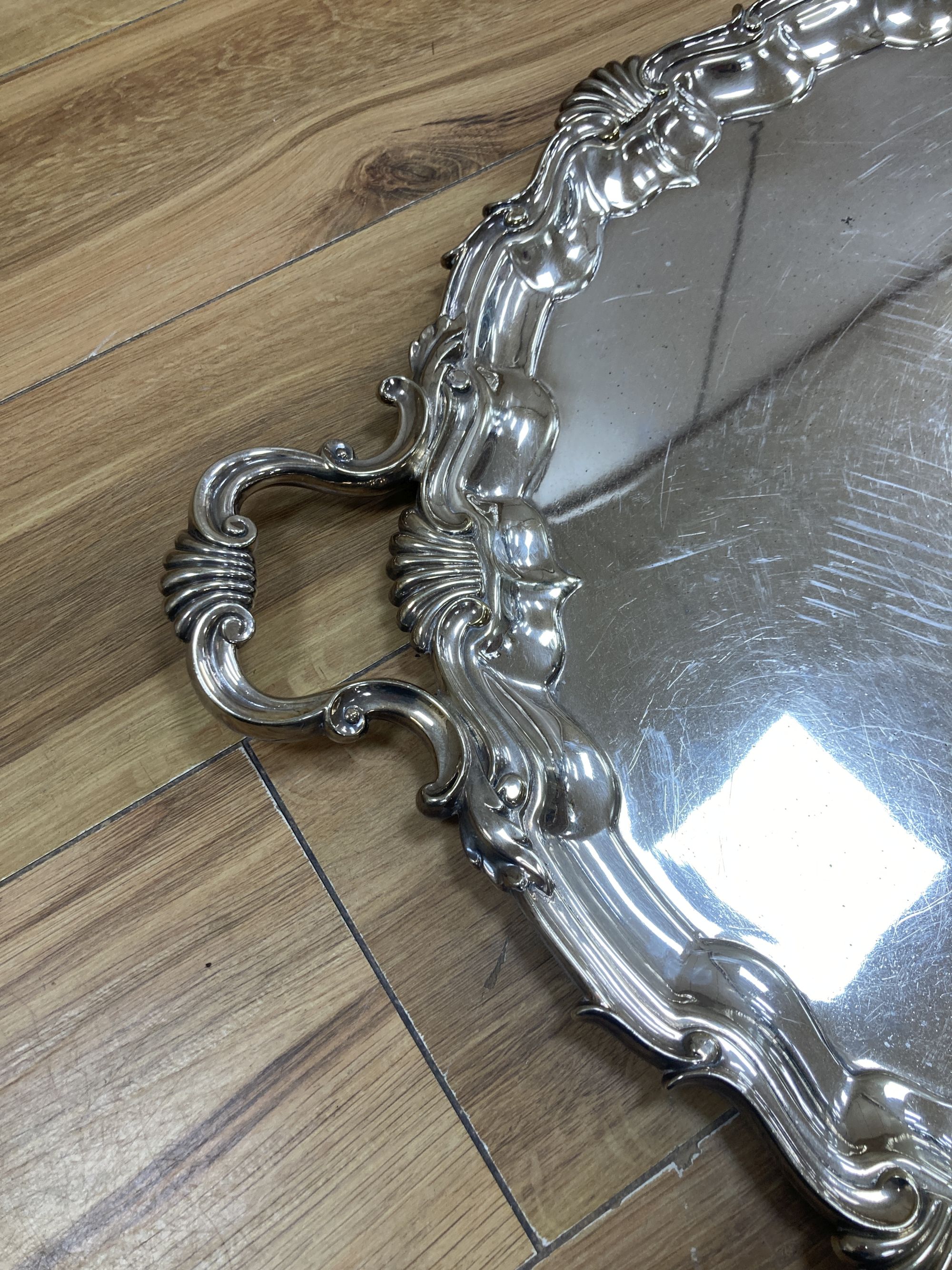 A large plated twin-handled shaped oval tray with shell and scroll border, L 76cm overall